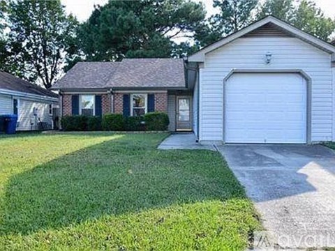 A house with a white garage door is surrounded by a green lawn.