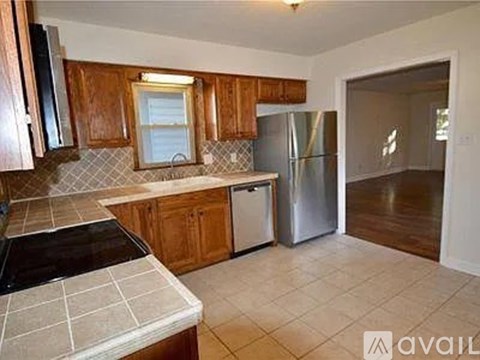 A kitchen with wooden cabinets and a stainless steel refrigerator.