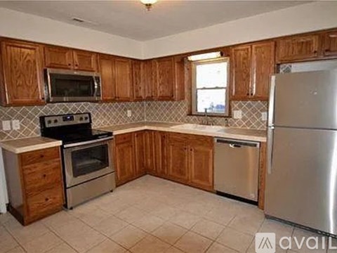 A kitchen with wooden cabinets and a stainless steel refrigerator.