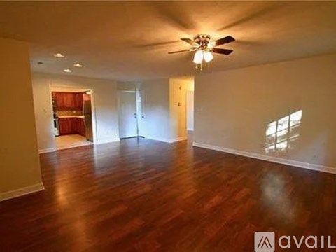 A spacious room with wooden floors and a ceiling fan.