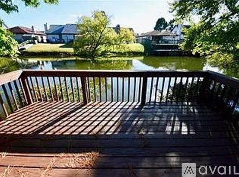 A wooden deck overlooking a body of water with houses in the background.