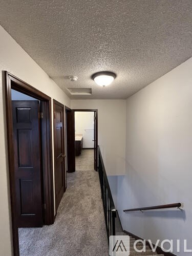 A hallway with a carpeted floor and a light on the ceiling.