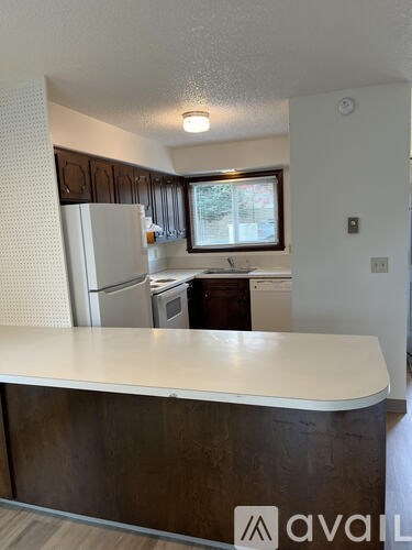 A kitchen with a white counter top and brown cabinets.