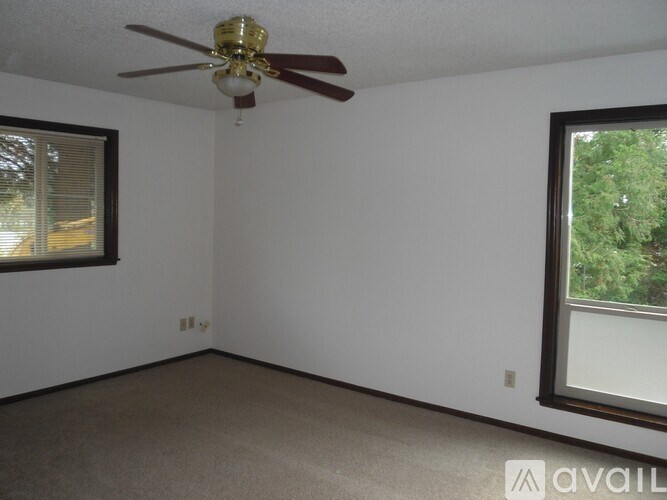 A room with a ceiling fan and two windows.