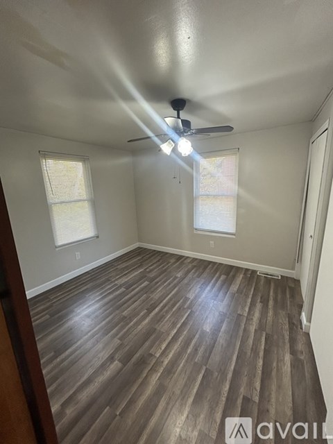 A room with a ceiling fan and wooden flooring.