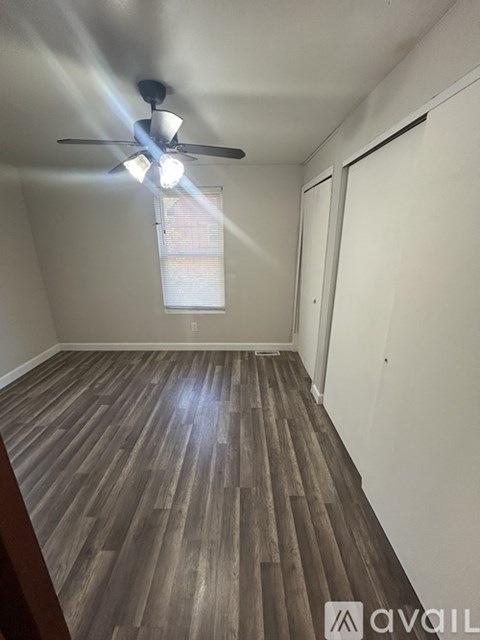 A room with wooden flooring and a ceiling fan with lights.
