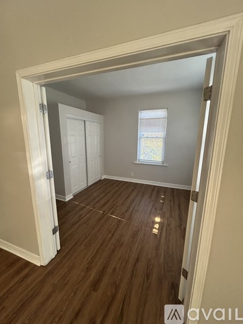 A room with wooden floors and a window is shown.