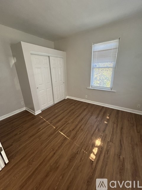 A room with wooden flooring and a window with blinds.