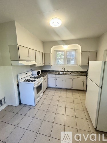 A kitchen with white appliances and cabinets.