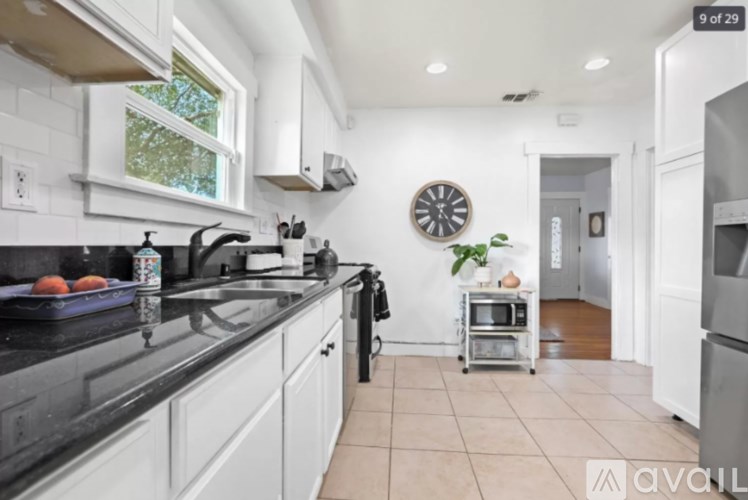 A kitchen with white cabinets and black countertops.