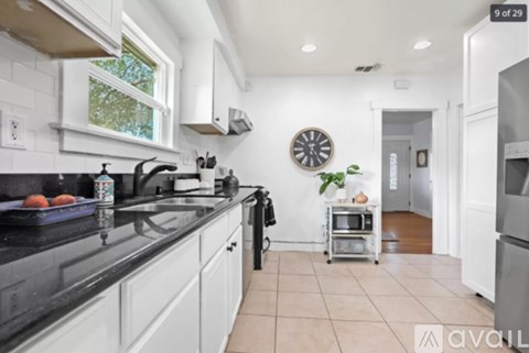 A kitchen with white cabinets and black countertops.