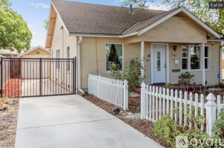A house with a white picket fence and a black gate.