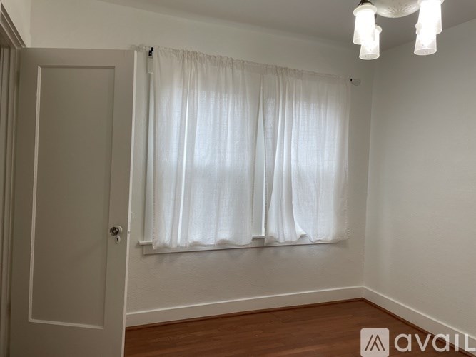 A room with a white curtain and wooden floor.