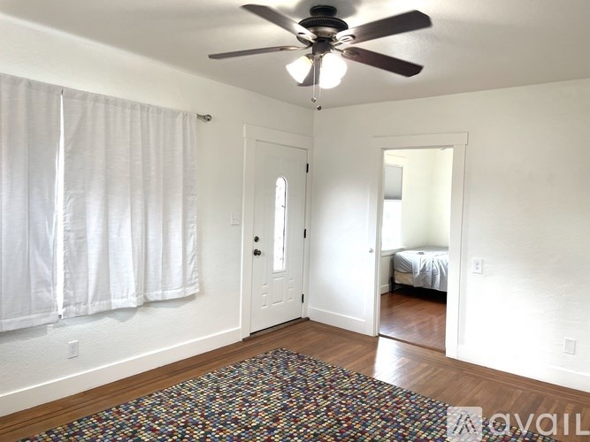 A room with a ceiling fan and a rug on the floor.