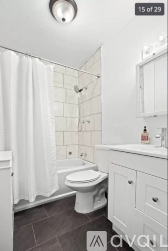 A white bathroom with a toilet, sink, and shower.