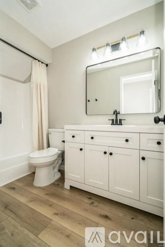 A bathroom with a toilet, sink, and mirror.