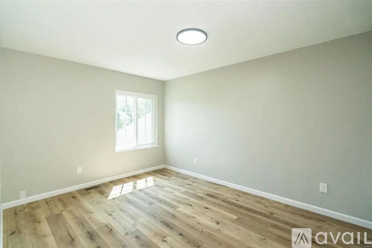A room with wooden flooring and a window letting in natural light.