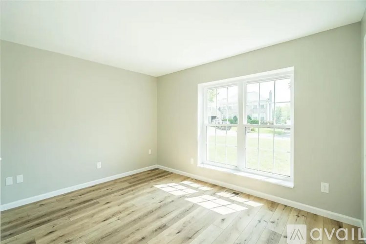 A room with wooden flooring and a large window.