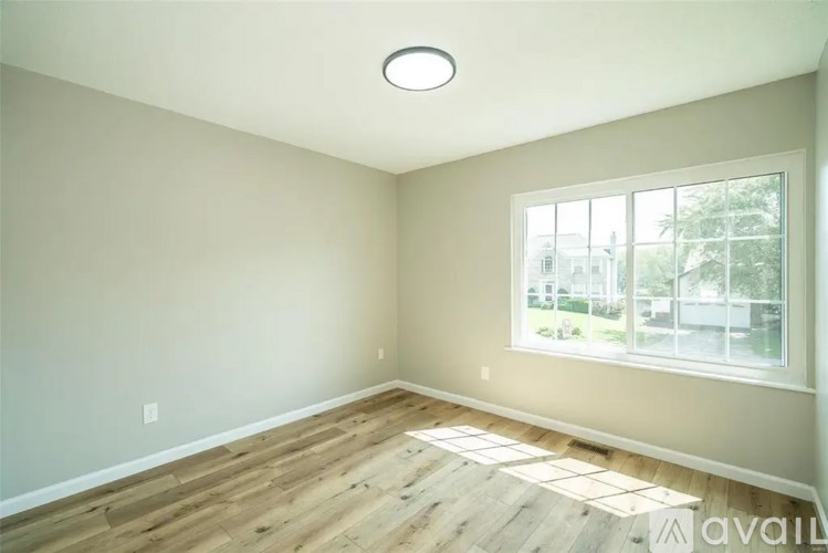 A room with wooden flooring and a large window.