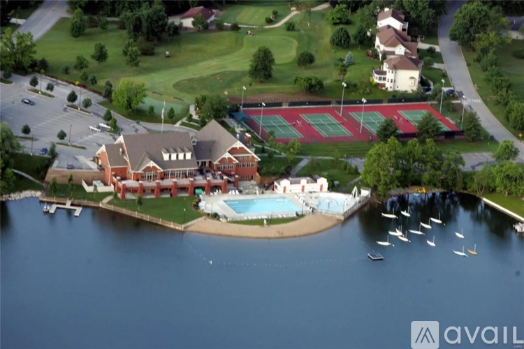 A large building with a red roof is surrounded by a green lawn and a body of water.