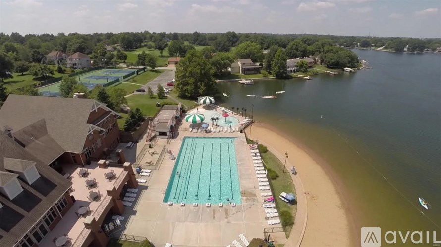 An aerial view of a swimming pool and beach area with a lake in the background.