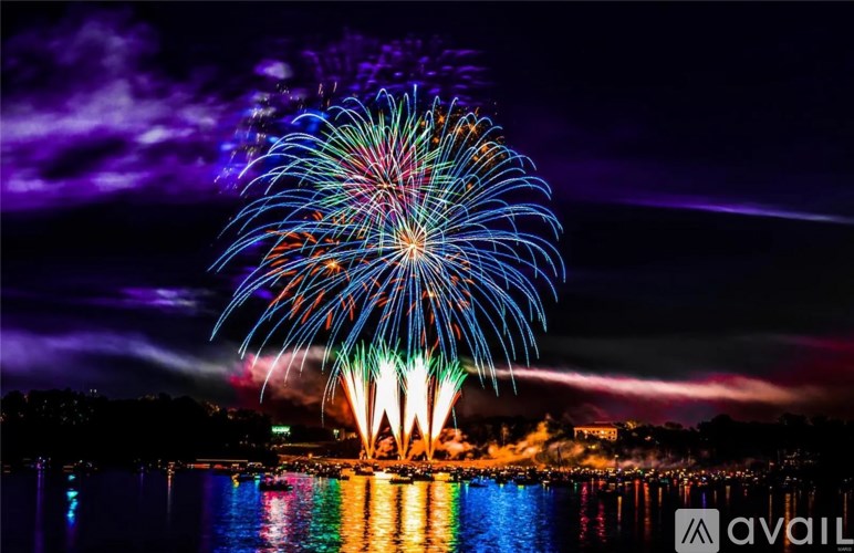 A vibrant fireworks display lights up the night sky over a body of water.