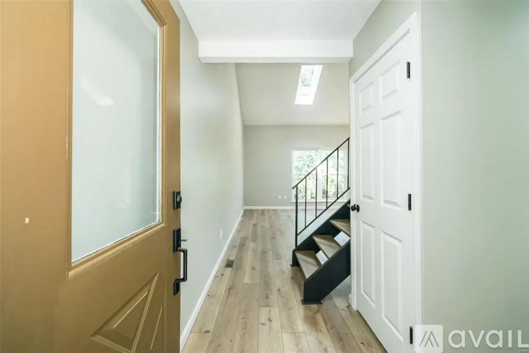 A hallway with a wooden floor and a black staircase.