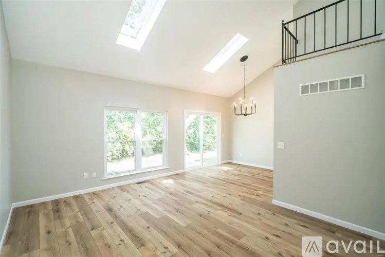 A spacious room with wooden flooring and skylight windows.