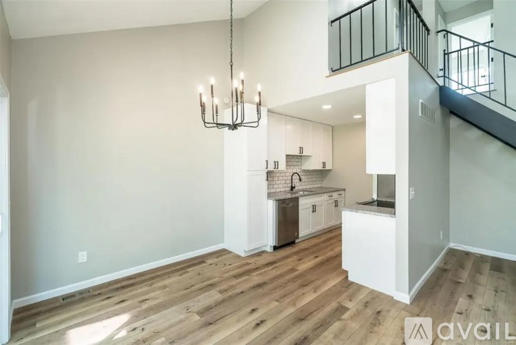 A modern kitchen with wooden floors and a chandelier.
