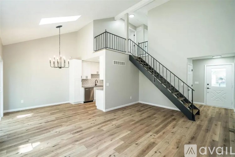 A spacious living room with wooden floors and a staircase leading to the upper level.
