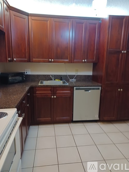 A kitchen with brown cabinets and a white dishwasher.