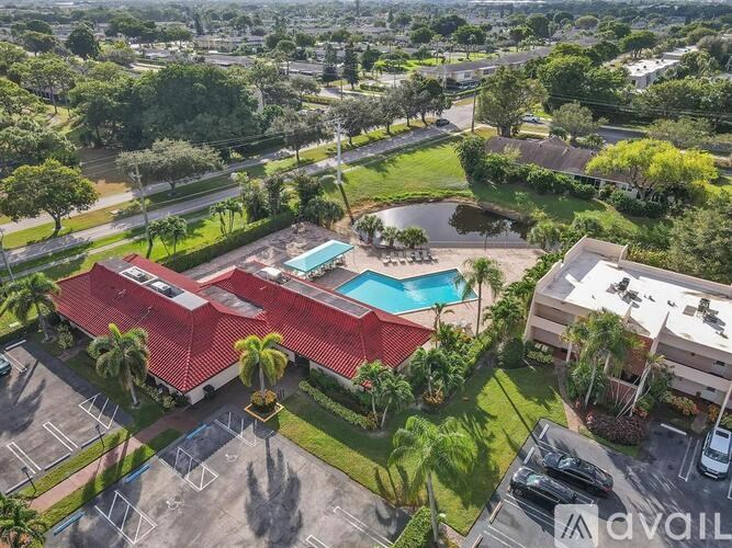 A large building with a red roof and a pool in the foreground.