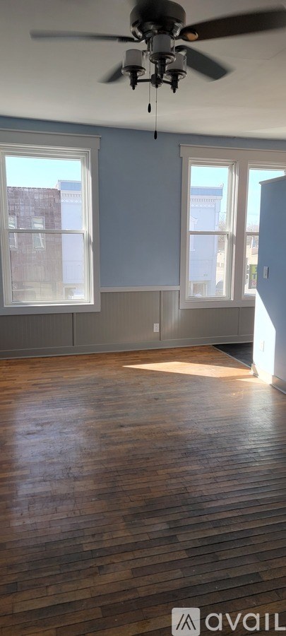 A room with a ceiling fan and wooden flooring.