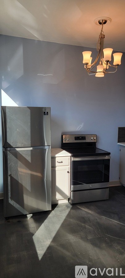 A kitchen with a fridge, oven and a chandelier.