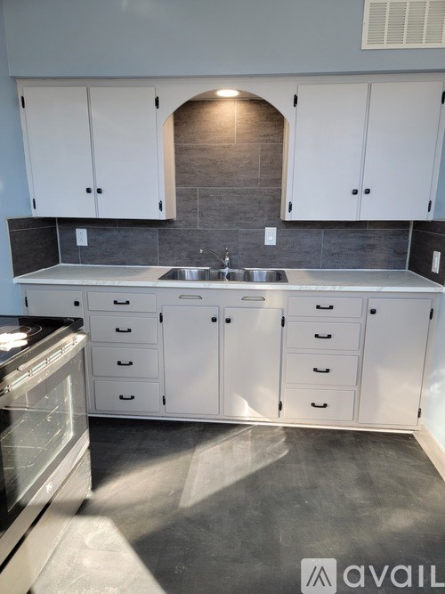 A kitchen with white cabinets and a stainless steel sink.