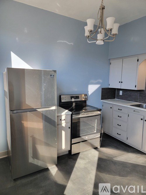A kitchen with a stainless steel refrigerator, a microwave, and white cabinets.