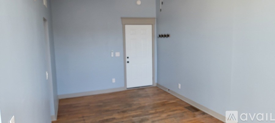 A room with a door and a wall with a switch.