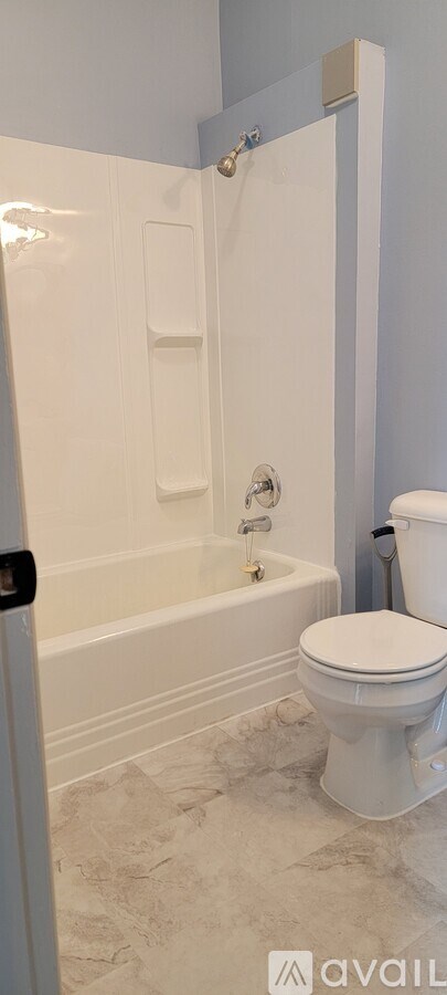 A white toilet in a bathroom with a white bathtub.
