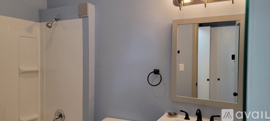 A bathroom with a white shower door and a mirror above a sink.