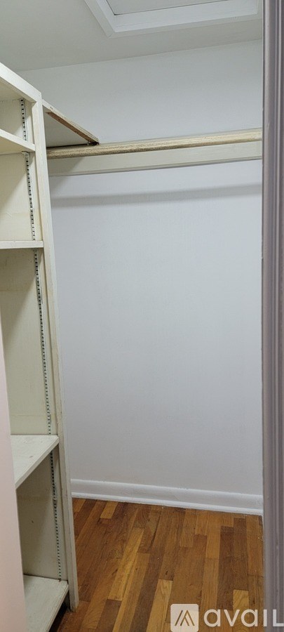A white shelving unit in a room with wooden flooring.