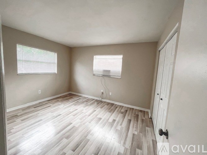 A room with light wood flooring and a window with blinds.