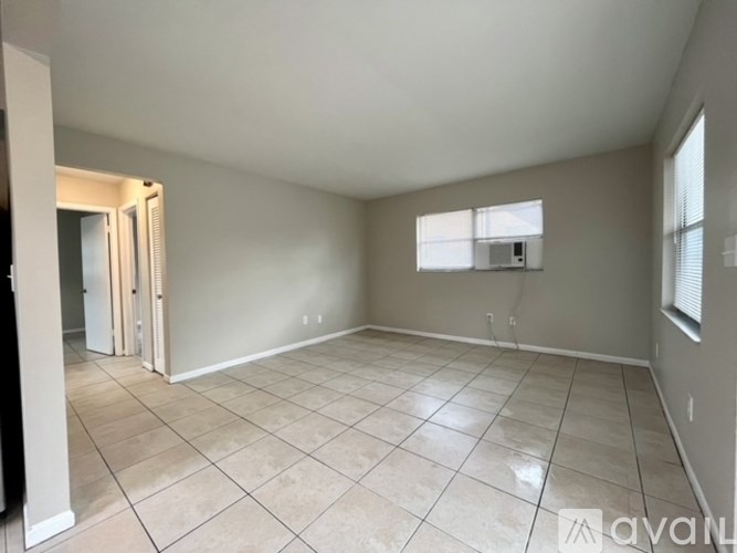 A spacious empty room with tiled flooring and a window.
