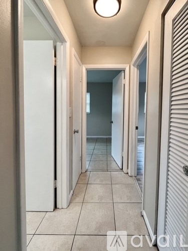A hallway with white doors and tiled floors.