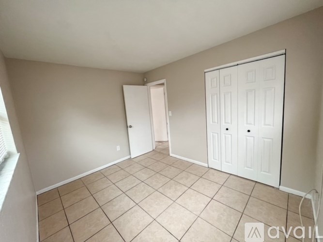 A room with a white door and a white closet with a white floor.