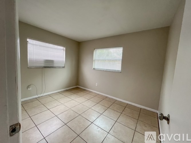 A room with tiled flooring and two windows.