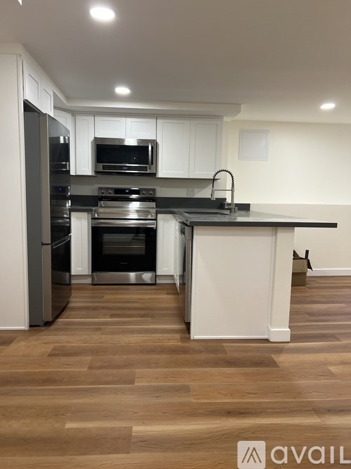 A kitchen with a black countertop and stainless steel appliances.