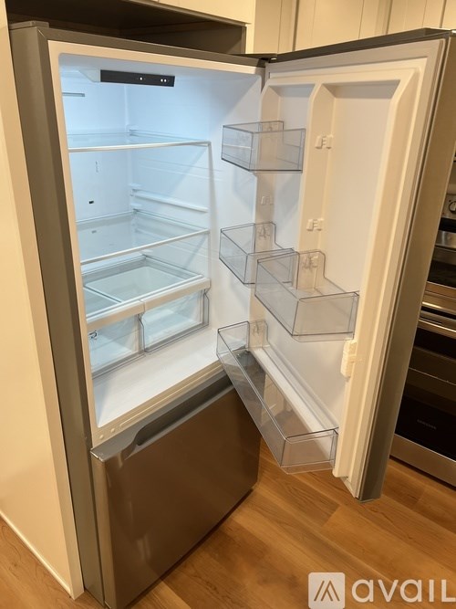 A white refrigerator with its door open and empty.