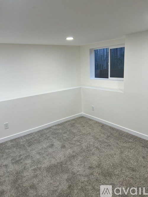 A room with a carpeted floor and a window with blinds.