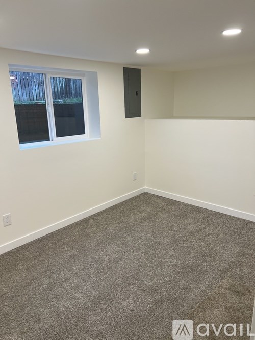A room with a window and a grey carpet.