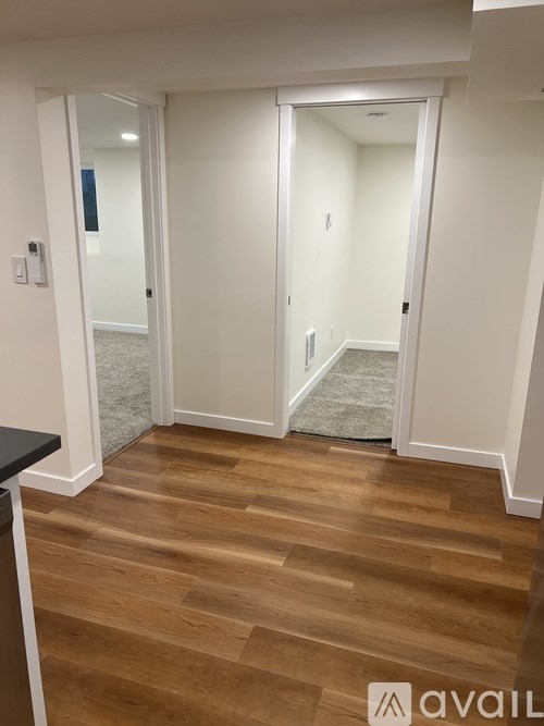 A hallway with a wooden floor and white walls.